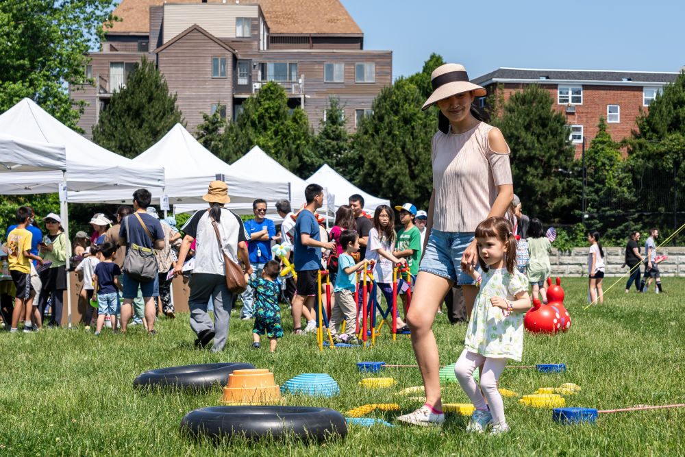 A woman and young girl enjoy the outdoor activities at the Family Fun Fair in Quincy, where many other families and their children browse tents and prepare to play games.