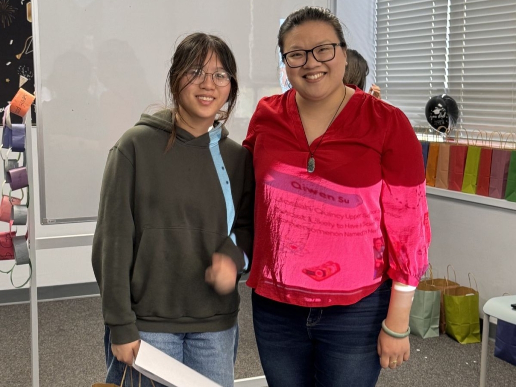 Two young adult Asian women pose together, smiling.